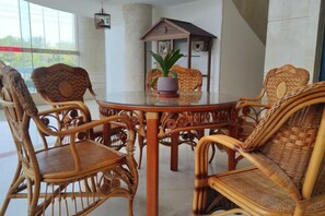 Una mesa redonda de madera con sillas de mimbre, una planta en maceta y un objeto decorativo sobre la mesa.