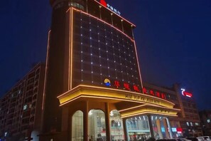 A hotel with a prominent sign, multiple floors, and a well-lit facade.