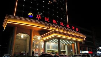 Un hotel con un letrero llamativo, varios pisos y una entrada bien iluminada.