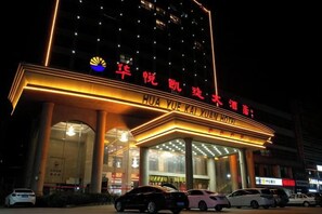 Un hotel con un letrero llamativo, varios pisos y una entrada bien iluminada.