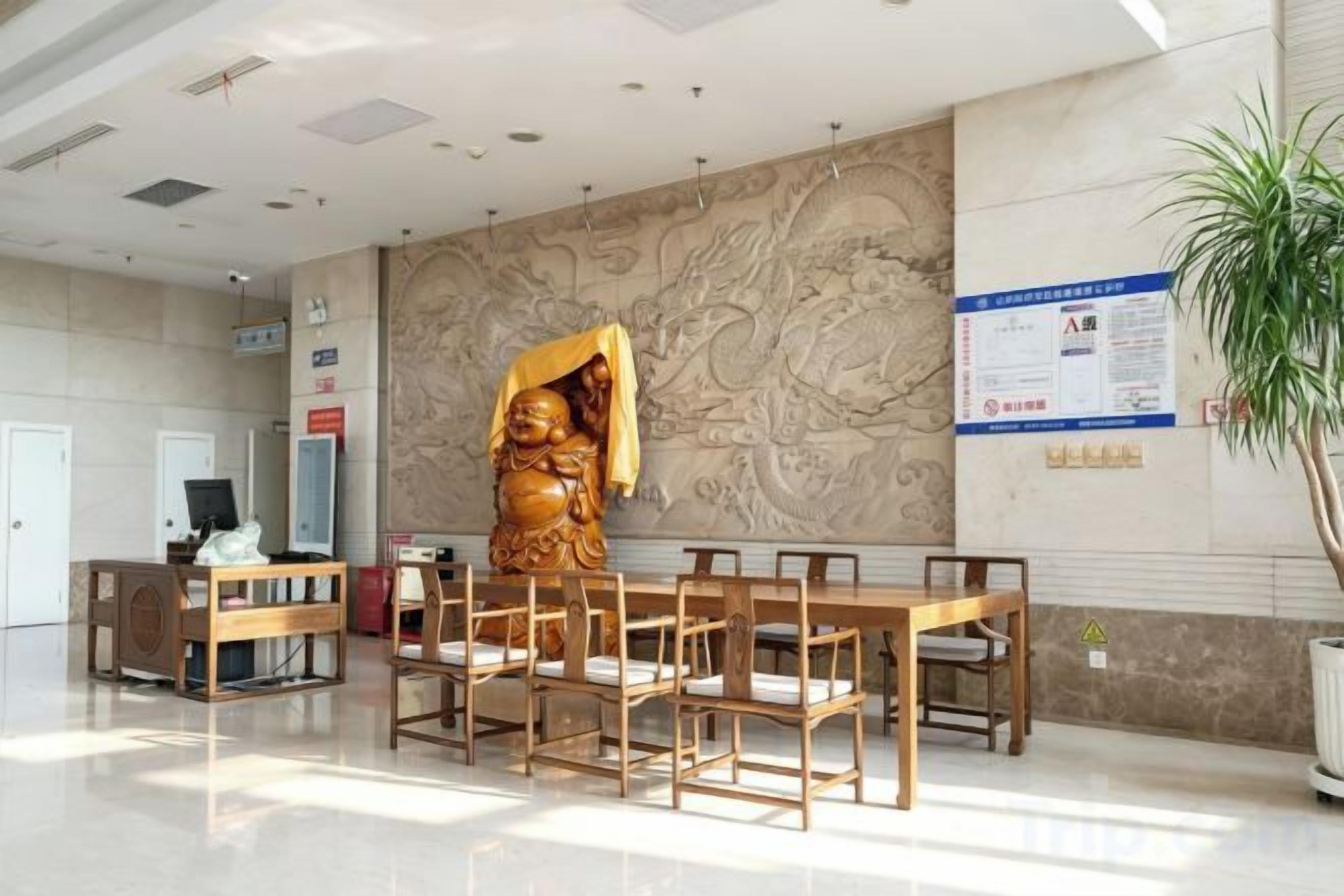A reception area with a large statue, a reception desk, and a plant.