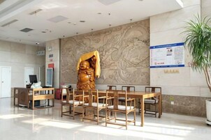 Un área de recepción con una estatua grande, un mostrador y una planta.
