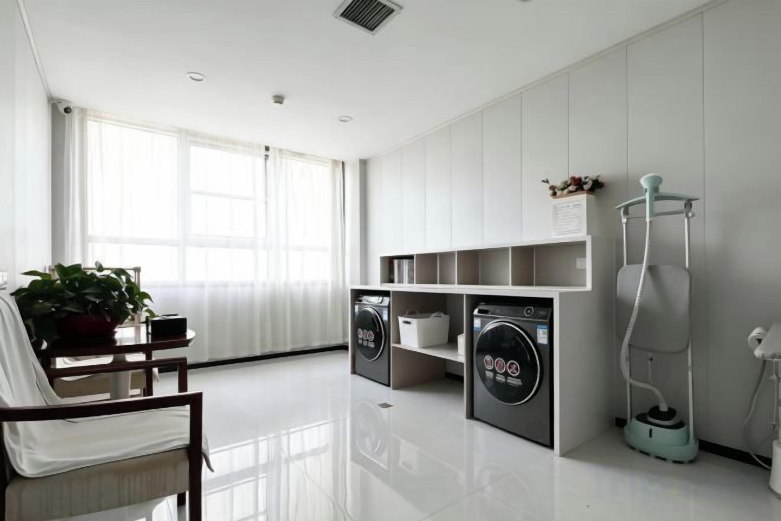 A modern laundry room with a washing machine, dryer, and a vacuum cleaner.