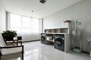 A modern laundry room with a washing machine, dryer, and a vacuum cleaner.