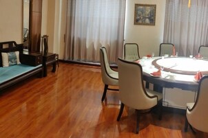 Una habitación con una mesa redonda preparada para comer, un sofá y una ventana con cortinas.