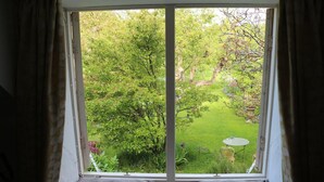 A room with a large window overlooking a lush garden.
