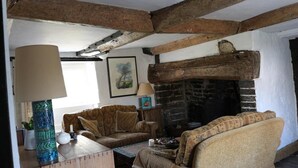 A cozy living room with exposed wooden beams, a fireplace, and comfortable seating.