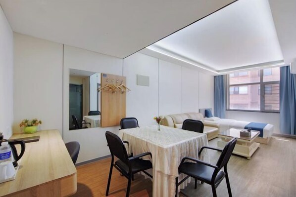 A modern hotel room with a dining area, a sofa, a coffee table, and a large window with curtains. - Shankee Collection Hotel (Shuozhou Ying County Public Security Bureau) (Ying County)