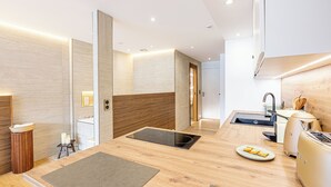 A modern kitchen with a wooden countertop, built-in stove, and a sink. - Le Rivage Alpin - vue lac et spa (Tresserve)