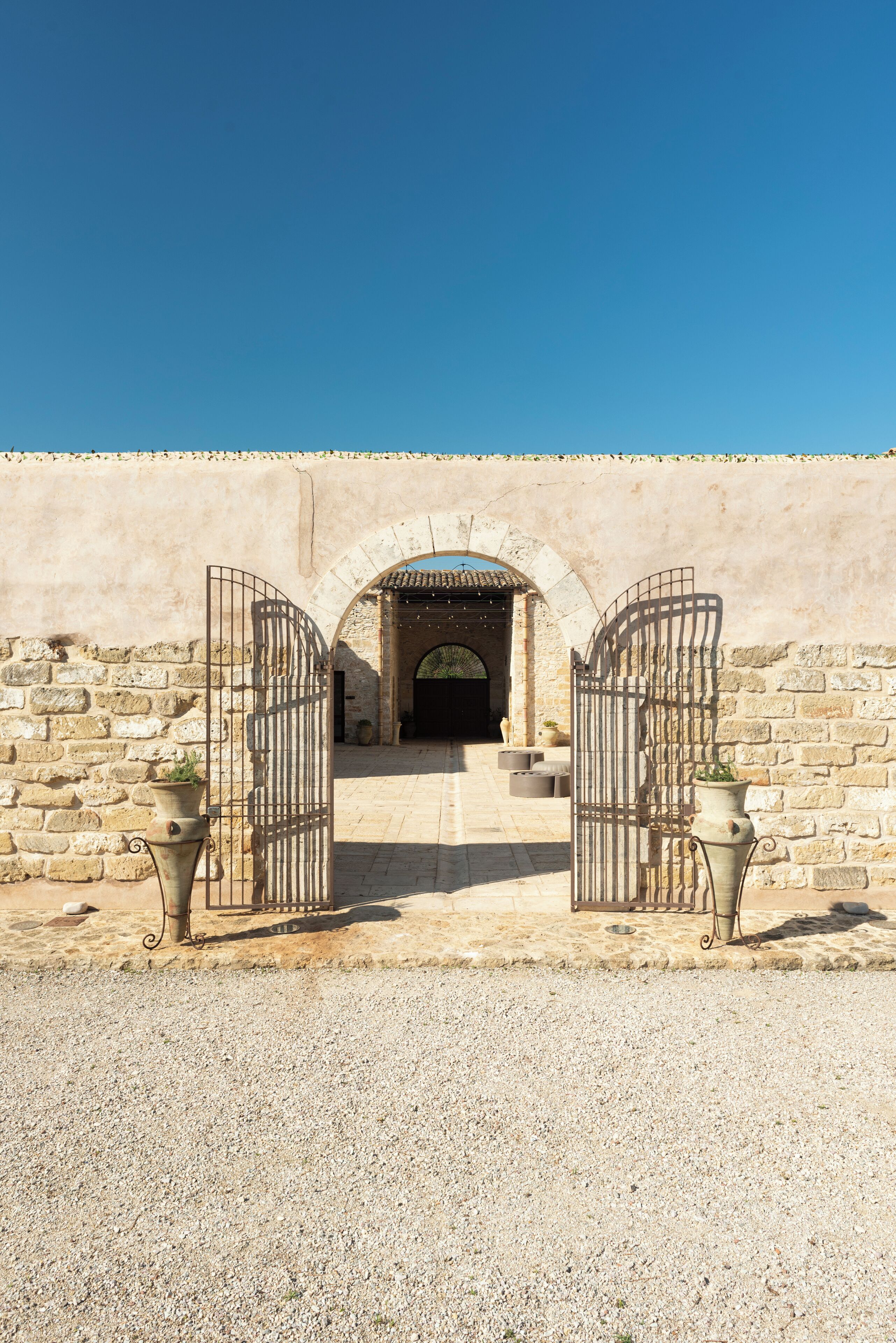 A stone wall with a gate leading to a covered entrance.