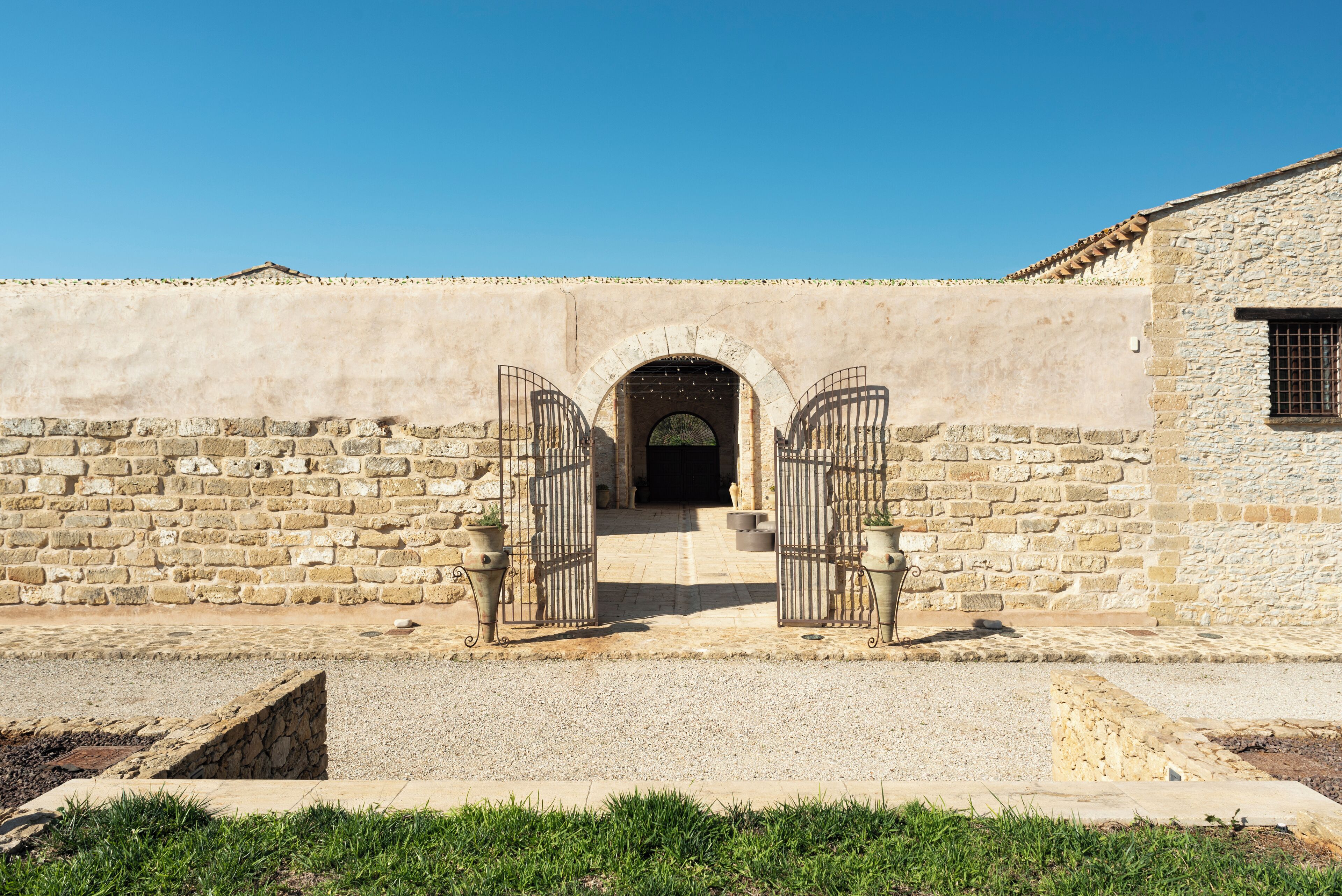 A stone building with a gate leading to an arched entrance.