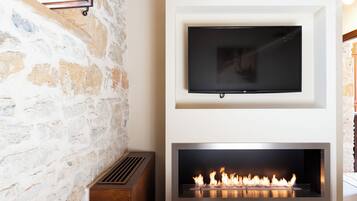 A stone wall, a mounted TV, and a fireplace with visible flames.