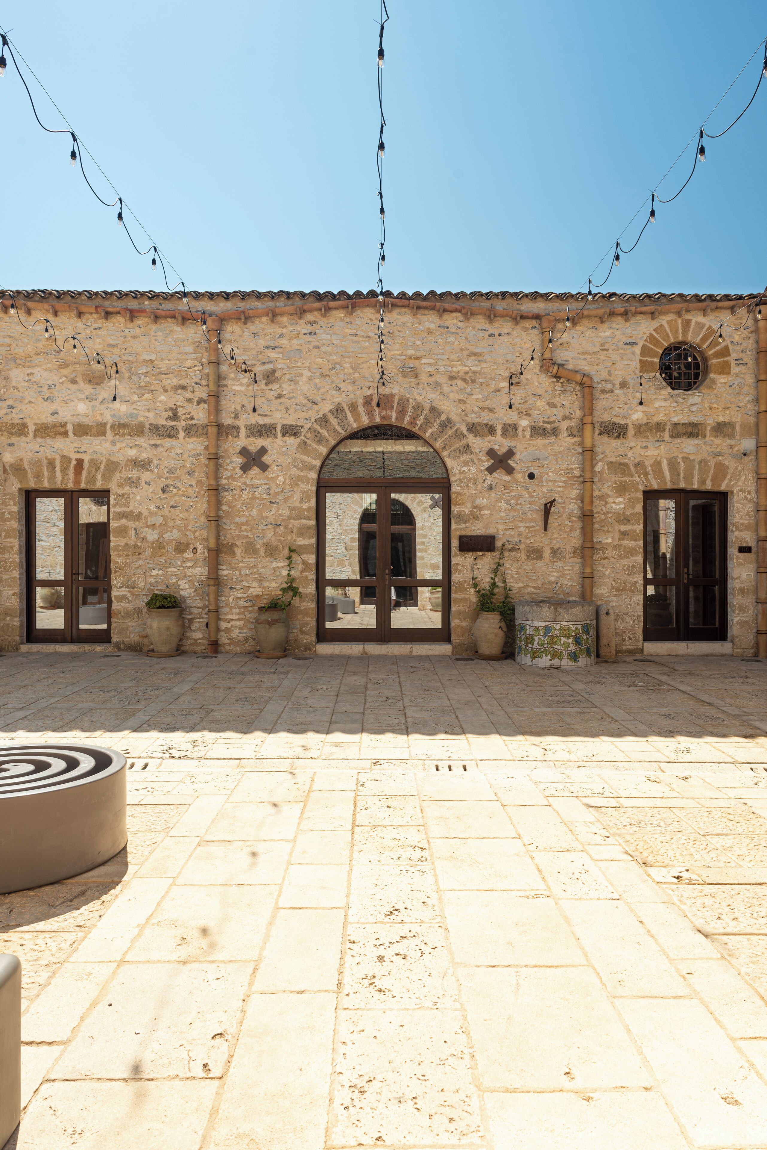 Un edificio con patio empedrado, paredes de piedra y arcos.