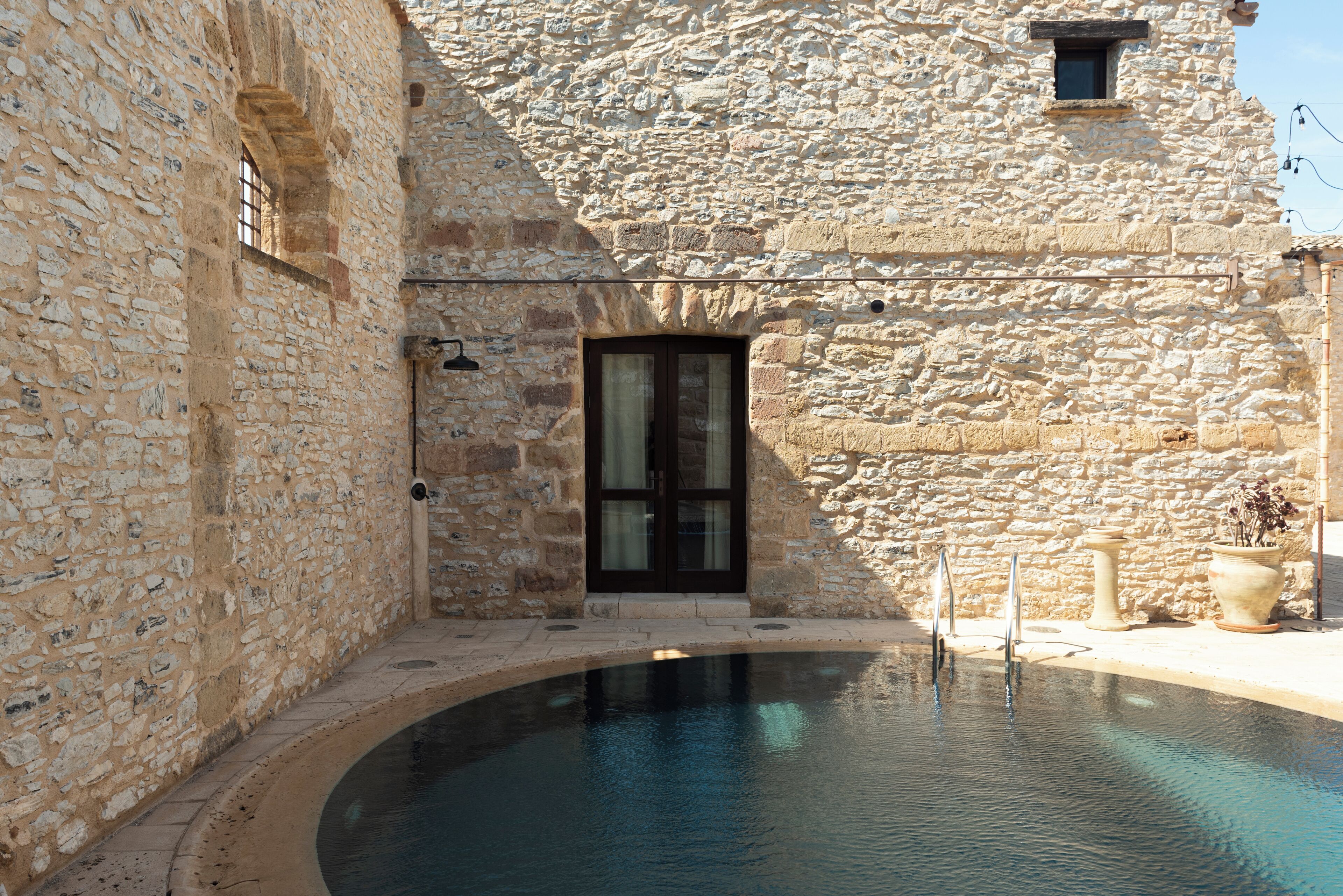 Ein Steinhaus mit Pool, einer Tür und einem kleinen Fenster.