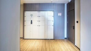 A hallway with a large, white, double-door entrance, wooden flooring, and a grey wall with a fire safety sign. - HanTing Hotel (Zhengzhou Zijingshan Subway Station) (Zhengzhou)
