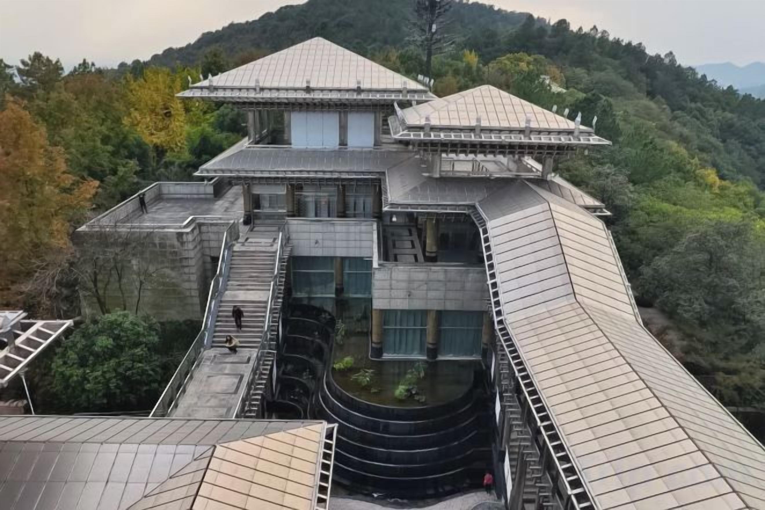 Un edificio japonés tradicional con tejado al estilo pagoda, un patio central y zonas boscosas circundantes.