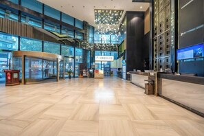 A spacious lobby with a modern design, featuring a reception desk, a seating area, and a large chandelier. - Manchester International Hotel (Hangzhou Qiushan Street Subway Station) (Hangzhou)