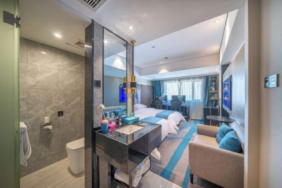 A modern hotel room with a bathroom, a sitting area, and a bed.