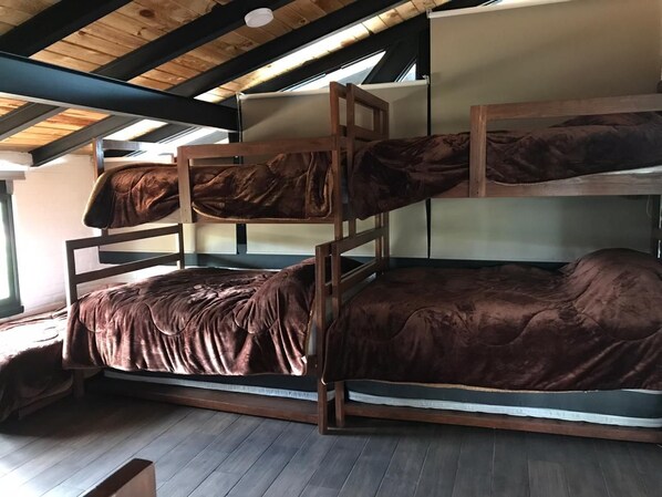 A bunk bed room with a wooden ceiling and a window providing natural light.