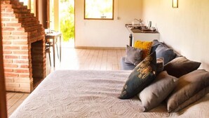 A spacious room with a large bed, a wooden ceiling, a brick fireplace, and a view of the outdoors. - Acogedora cabaña en el bosque Tapalpa (Tapalpa)