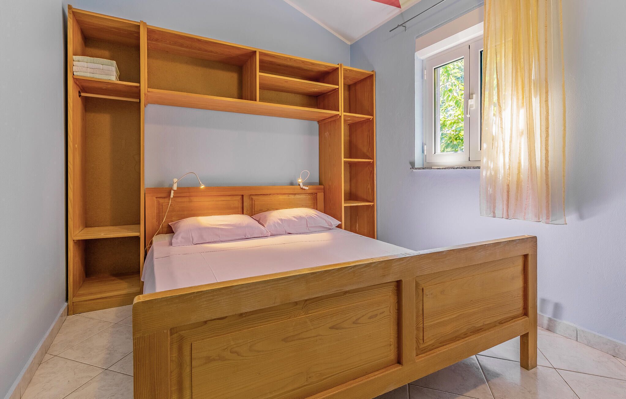 Een slaapkamer met een houten bed, een nachtkastje en inbouwplanken.