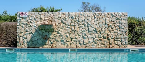 Una piscina al aire libre, sombrillas, sillones reclinables de piscina