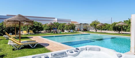 A swimming pool with lounge chairs and a hot tub.