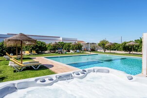 Piscina com espreguiçadeiras e banheira de hidromassagem.