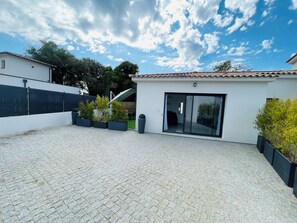Stroll through the serene courtyard, lined with potted plants, to the glass door entrance of this residence.