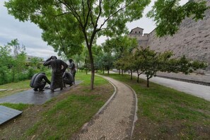 A pathway with sculptures, a brick wall, and a building in the background. - Qininn Qiaozhai Minsu Fengqing Branch (Pingyao County)
