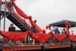 Una escalera con cortinas rojas, baranda metálica y una plataforma con gente.