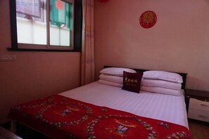 A bedroom with a bed, pillows, a red blanket, a nightstand, a window, and a wall decoration. - Qininn Qiaozhai Minsu Fengqing Branch (Pingyao County)