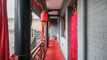 A corridor with red lanterns, a red carpet, and a brick wall.