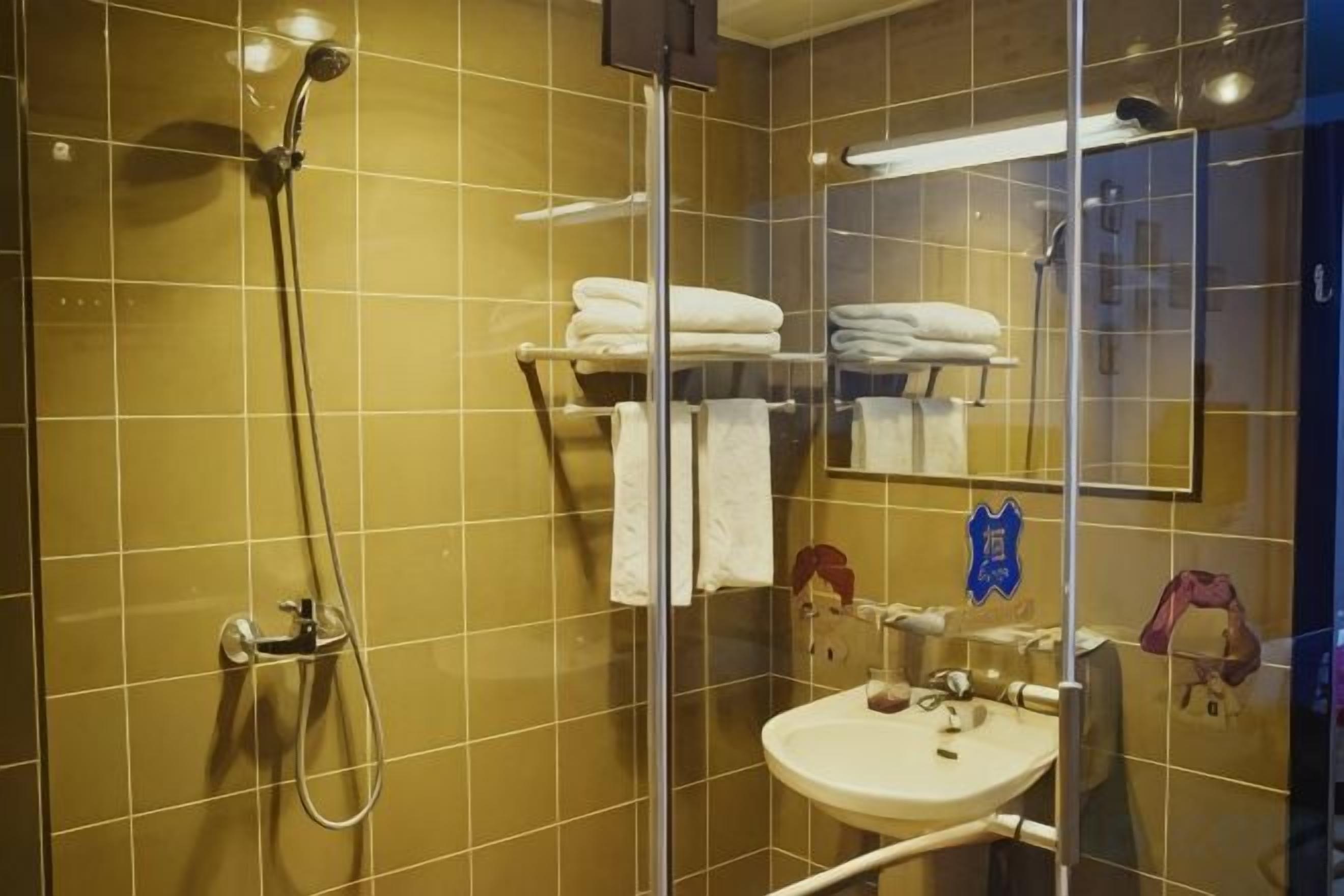 A bathroom with a glass shower enclosure, a sink, and a towel rack.