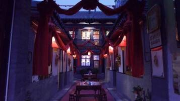 A corridor with traditional architecture, a table, and potted plants.