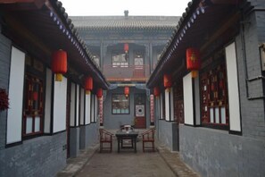 A corridor with traditional architecture, a table with chairs, and red lanterns. - Qininn Qiaozhai Minsu Fengqing Branch (Pingyao County)