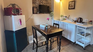 A compact kitchen with a stone wall, a wooden ceiling, and a small dining area with a table and chairs.