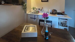 A kitchen with a stone wall, a wooden ceiling, a sink, a stove, and a vase with a flower.