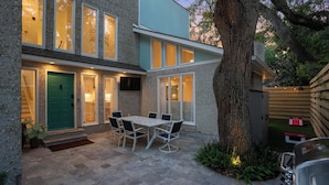 Een modern huis met een terras, een eettafel en een barbecue.