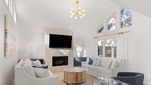 Een moderne woonkamer met een open haard, een flatscreen televisie en een groot raam.
