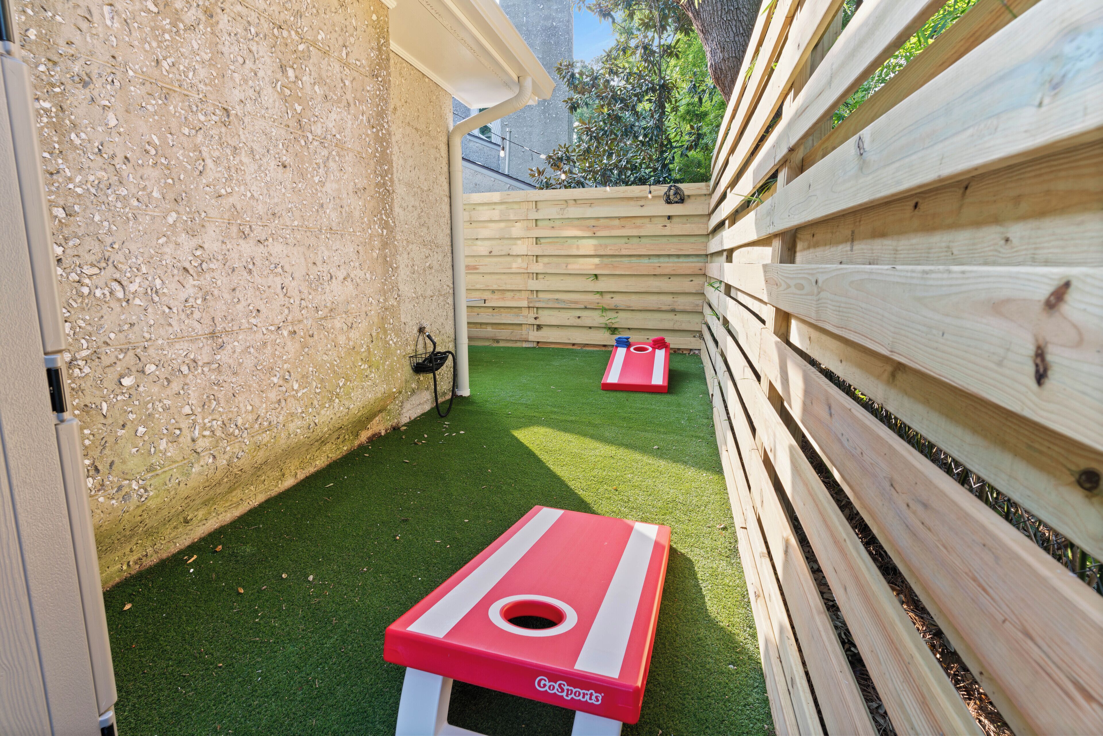 A small outdoor area with artificial turf, two GoSports tables, and a wooden fence.