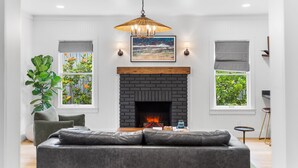 A modern living room with a fireplace, a sofa, a coffee table, and a large plant.