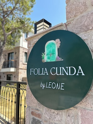 Μια πινακίδα με το κείμενο «FOLIA CUNDA by LEONE» σε πράσινο φόντο.
