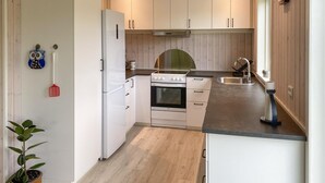 A compact kitchen with white cabinets, a built-in oven, a stove, and a sink.