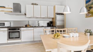 Eine moderne Küche mit weißen Schränken, Edelstahlgeräten und einem Holzespeisetisch, gedeckt mit Tellern und Tassen.