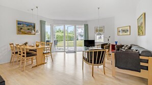 Ein geräumiges Wohnzimmer mit einem Holzesstisch, Stühlen, einer Couch und einem Fernseher.