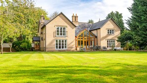A two-story house with a large front lawn, a conservatory, and a patio area. - Norwich Luxury Getaway With 4 Bedrooms & Annex (Norwich)