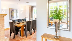 A dining area with a wooden table and chairs, a tiled floor, and a framed artwork on the wall. - Norwich Luxury Getaway With 4 Bedrooms & Annex (Norwich)