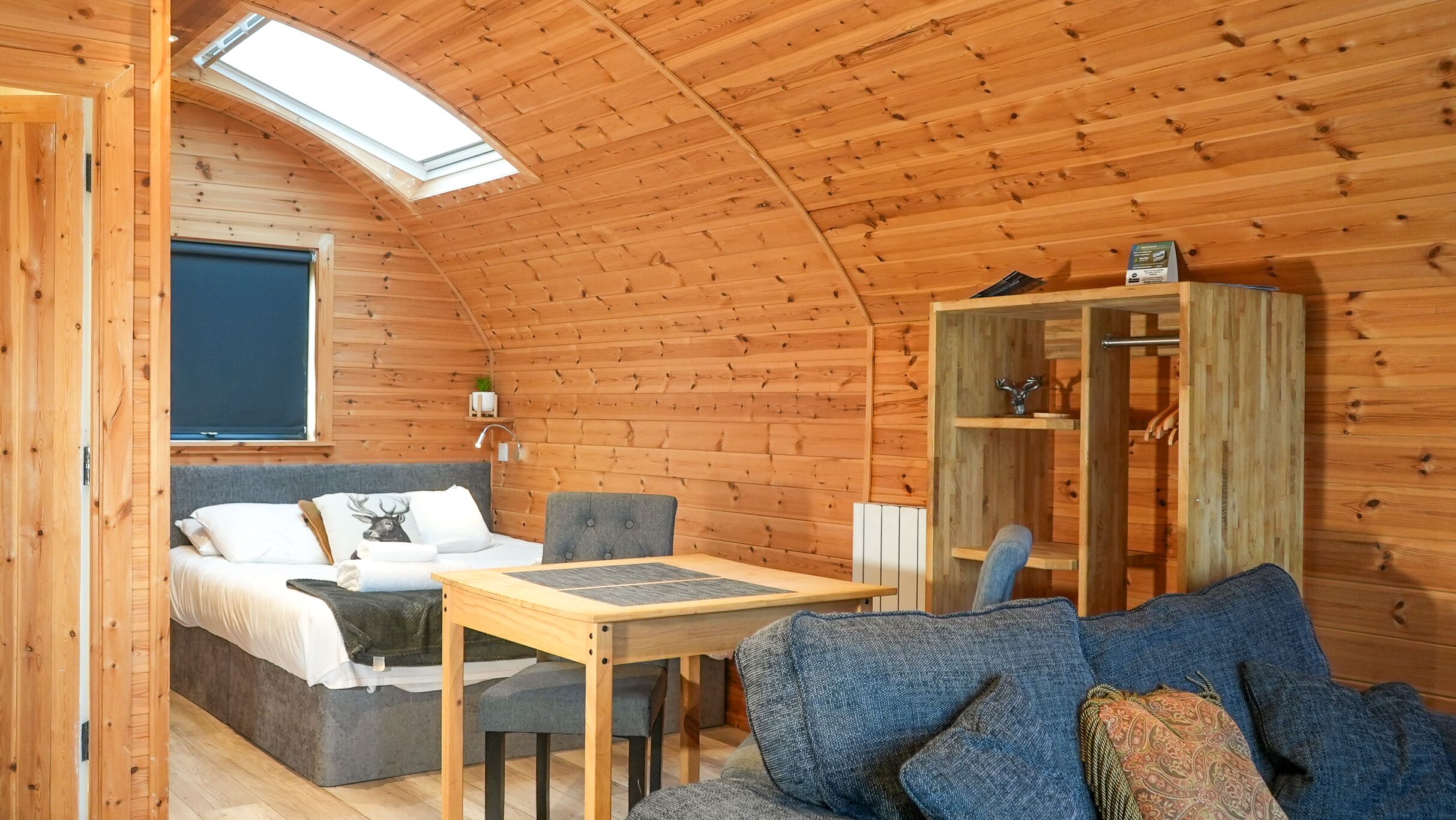A cozy cabin interior with a bed, sofa, table, and a wardrobe.