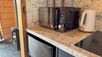 Una cocina con encimera de mármol, cafetera, microondas y refrigerador.